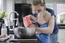 Madre ayudando hijo hornear pastel - foto de stock