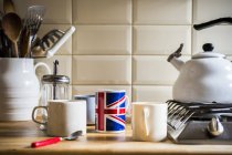 Balcão de cozinha com jarro de utensílios e canecas de café — Fotografia de Stock