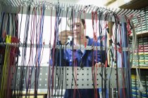 Electricista masculino seleccionando cable de alimentación en taller - foto de stock