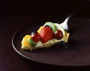 Шматочок полуниці, ківі, апельсина та виноградного пирога на тарілці — стокове фото