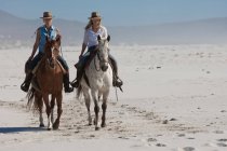 2 personnes à cheval sur la plage — Photo de stock