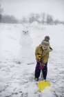 Девушка убирает снег перед снеговиком, Лейкфилд, Онтарио, Канада — стоковое фото