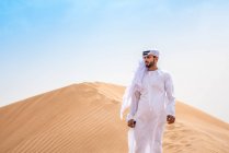 Middle eastern man wearing traditional clothes on desert dune, Dubai, United Arab Emirates — Stock Photo