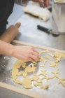 Abgeschnittenes Bild eines Bäckers, der Teig mit Schimmel in der Küche schneidet — Stockfoto