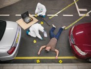 Científicos forenses en la escena del crimen en un centro de entrenamiento con una persona actuando como cuerpo en el suelo - foto de stock