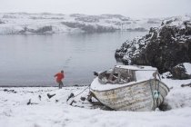 Un homme jette de la pierre dans l'eau d'un lac en hiver, Islande — Photo de stock