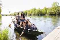 Pequeño grupo de amigos adultos jóvenes en barco fila en el agua - foto de stock