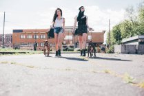 Zwei junge Frauen spazieren mit Pitbull-Hund in städtischer Wohnsiedlung — Stockfoto