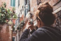 Vista sulla spalla di una donna che fotografa edifici su smartphone, Venezia, Italia — Foto stock