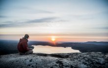 Junge Wanderin blickt bei Sonnenuntergang über fernen See — Stockfoto