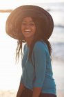 Mulher sorridente usando chapéu de sol na praia — Fotografia de Stock