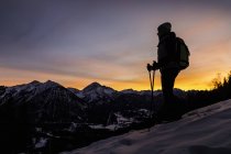 Joven excursionista mirando desde la ladera de la montaña al atardecer, Reutte, Tirol, Austria - foto de stock