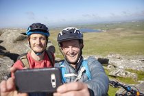 Cyclists with on rocky outcrop taking selfie — Stock Photo