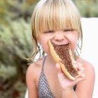 Retrato de una chica comiendo un sándwich de chocolate - foto de stock