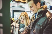 Молодая пара покупает билеты на поезд в автомате — стоковое фото
