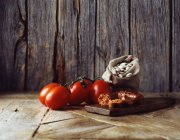 Tomates, chorizo y judías mantequilla en saco de arpillera sobre tabla de cortar de madera - foto de stock