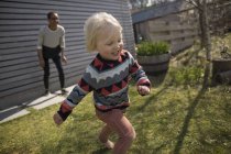 Junge läuft vor Mutter in Garten und lächelt — Stockfoto