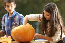 Siblings hollowing out pumpkin at home — Stock Photo