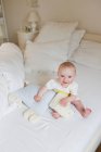 Bambino sorridente seduto sul letto — Foto stock