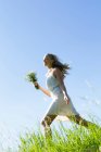 Frau trägt Blumenstrauß im hohen Gras — Stockfoto
