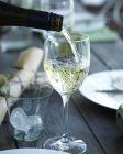 Primer plano de vino blanco vertiendo en el vaso - foto de stock