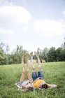 Jovem casal deitado na grama no campo, pernas levantadas — Fotografia de Stock