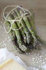 Bunch of asparagus on table with sea salt and cheese — Stock Photo