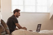 Uomo a letto con computer portatile — Foto stock