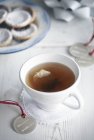 Xícara de chá e etiqueta de presente na mesa — Fotografia de Stock