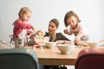 Mother and children baking, mixing batter — Stock Photo