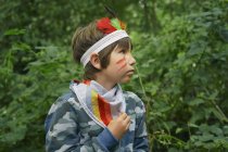 Хлопчик одягнений в обличчя фарба грає в лісі — стокове фото