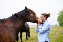 Woman with her face to horse's muzzle in field — Stock Photo