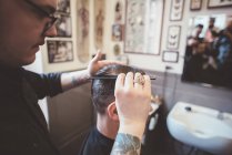 Barbeiro pentear gel no cabelo do cliente na barbearia — Fotografia de Stock