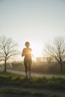 Молода жінка біжить, біжить на заході сонця — стокове фото