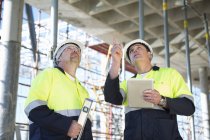 Gestionnaire de site et constructeur regardant vers le haut sur le chantier de construction — Photo de stock