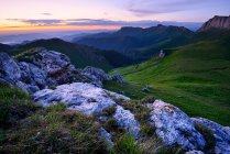 Краєвид з зеленими пагорбами в сутінках з хмарним небом — стокове фото