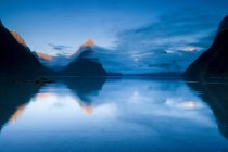 Montañas rurales reflejadas en un lago tranquilo - foto de stock