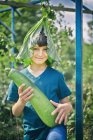 Portrait of boy with leaf hat and marrow on allotment — Stock Photo
