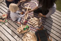 Madre e hijo jugando con la pista de tren de juguete de madera, ángulo alto - foto de stock