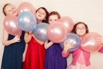 Portrait de quatre filles tenant des ballons — Photo de stock