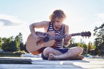 Junger Mann spielt Gitarre auf Seebrücke, Gavle, Schweden — Stockfoto
