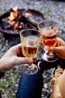 Duas pessoas brindam com bebidas em copos de vinho perto do fogo — Fotografia de Stock