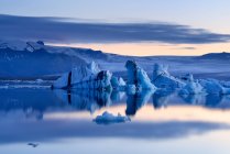 Icebergs reflejando en el agua y el cielo nublado en el fondo, Laguna de Jokulsarlon, Islandia - foto de stock