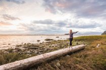 Donna in equilibrio sul tronco d'albero a Wreck Beach, Vancouver, Canada — Foto stock