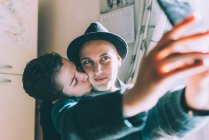 Молодая лесбийская пара делает селфи со смартфона на кухне — стоковое фото