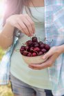 Cropped image of young woman with bowl of cherries — Stock Photo