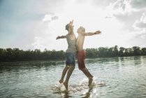Young men chest bumping in lake — Stock Photo