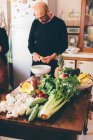 Senior schneidet Artischocken am Küchentisch — Stockfoto