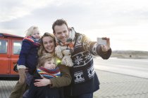 Metà uomo adulto prendendo un selfie di famiglia nel parcheggio costiero — Foto stock