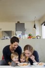 Familia con dos hijas comiendo espaguetis - foto de stock